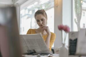 giovane donna seduta nel coworking spazio, lettura giornale foto