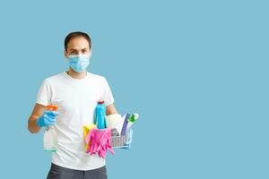 uomo fare appartamento pulizia. infezione prevenzione e controllo di epidemico. protettivo guanti e maschera. blu sfondo foto