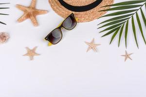 accessori da spiaggia, occhiali e cappello con conchiglie e stelle marine su sfondo colorato foto