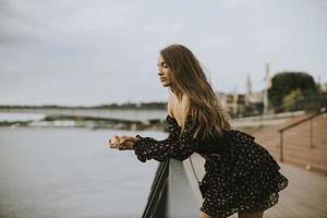giovane donna bruna capelli lunghi in piedi sulla riva del fiume