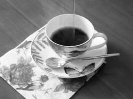 tazza da caffè di bellezza in piedi sul tavolo di legno con caffè scuro e gustoso foto