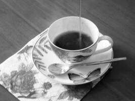 tazza da caffè di bellezza in piedi sul tavolo di legno con caffè scuro e gustoso foto
