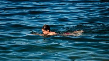 una giovane ragazza nuota nelle acque cristalline di un lago di montagna.