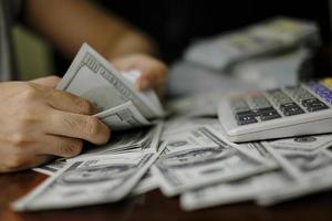 uomini d'affari donne che contano soldi su una pila di 100 dollari americani banconote un sacco di soldi