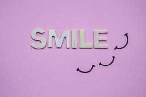 parola sorriso con lettere in legno sullo sfondo viola foto