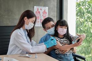 ragazza asiatica che si fa un selfie mentre un medico sta vaccinando. foto