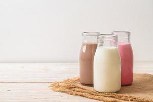 raccolta di bevande al cioccolato al latte, latte rosa e latte fresco in bottiglia su tavola di legno