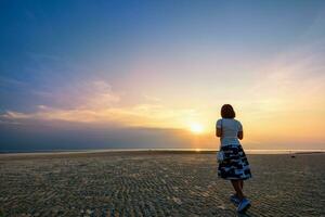 donna passeggiando su il spiaggia a tramonto foto