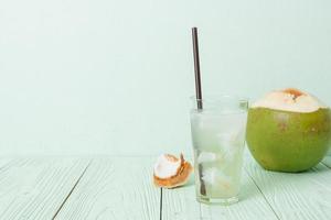 acqua di cocco o succo di cocco in bicchiere con cubetti di ghiaccio foto