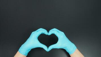 un' mano è fare amore mano cartello e indossare chirurgico guanti su nero sfondo. foto