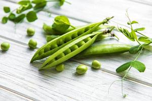 piselli verdi su un fondo di legno bianco. sfondo di cibo sano. foto