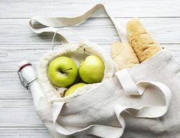 mele fresche, latte e pane in sacchetto di cotone ecologico foto