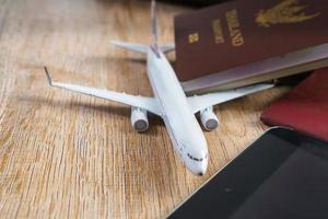 borsa in pelle e piccolo modello di aereo su sfondo di tavola di legno foto