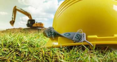 casco giallo ed escavatore al lavoro in cantiere foto