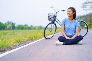 ragazza con bici, donna seduta per strada nel parco e bicicletta