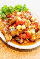 cernia fritta condita con salsa dolce, acida e piccante su piatto bianco - stile cibo asiatico