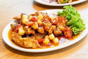 cernia fritta condita con salsa dolce, acida e piccante su piatto bianco - stile cibo asiatico