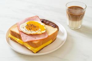 pane fatto in casa formaggio tostato condita con prosciutto e uovo fritto con salsiccia di maiale e caffè per colazione foto