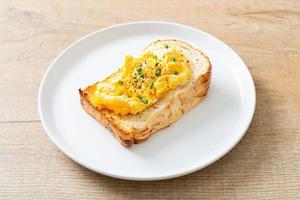 pane tostato con uova strapazzate su piatto bianco foto