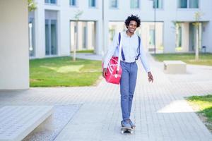 uomo d'affari nero che guida skateboard vicino all'edificio per uffici. foto