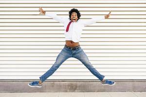 uomo d'affari nero che salta all'aperto. uomo con i capelli afro. foto