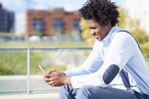 uomo di colore con acconciatura afro che usa uno smartphone foto