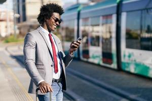 sorridente uomo d'affari nero in attesa del prossimo treno foto