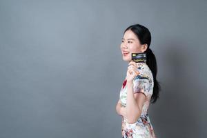 la donna asiatica indossa un abito tradizionale cinese con la carta di credito in mano foto