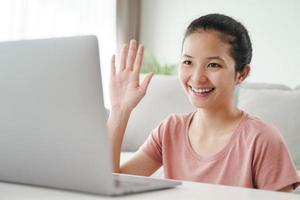 giovane donna che utilizza il computer portatile per la videoconferenza agitando il gesto della mano. foto