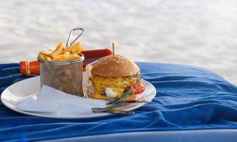 hamburger classico con formaggio sulla spiaggia foto