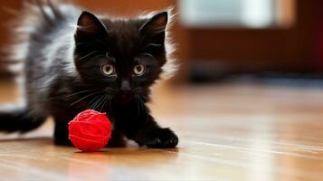nero gattino scherzosamente chasing un' rosso palla di filato su un' legno duro pavimento. generativo ai foto