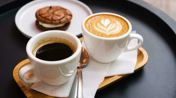 un' tazza di cappuccino e tazza di caffè con cioccolato biscotto su il nero tavolo nel bar. avvicinamento. foto