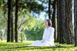 donna rilassante praticante meditazione nel il pino foresta per raggiungere felicità a partire dal interno pace saggezza con mattina leggero per salutare mente e anima concetto foto