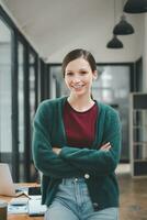 riuscito donna d'affari in piedi nel creativo ufficio e guardare a telecamera. donna imprenditore nel un' coworking spazio sorridente. foto