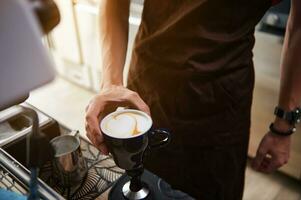 avvicinamento. tazza con cappuccino nel maschio barista mano. foto