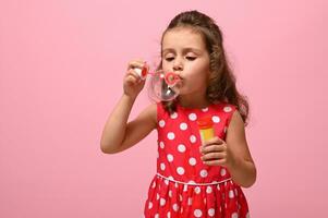 compleanno evento concetto, contento donna di giorno, bambini protezione giorno. adorabile bambino, bella compleanno ragazza indossare alla moda rosa vestito con bianca polka puntini di partenza sapone bolle su rosa sfondo foto