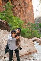 Due ragazze escursioni a piedi nel il montagne. adolescenziale ragazze avendo divertimento e a piedi su sentiero nel Sion nazionale parco, Utah, Stati Uniti d'America foto