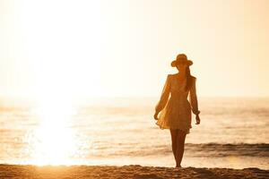 giovane contento donna su il spiaggia godere sua estate vacanza. bellissimo donna nel cappello è contento e calma nel sua restare su il spiaggia foto