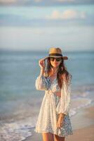 giovane bellissimo donna a cannuccia cappello su il spiaggia a tramonto foto