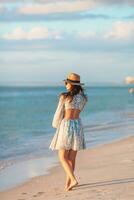 giovane contento donna su il spiaggia godere sua estate vacanza. bellissimo donna nel cappello è contento e calma nel sua restare su il spiaggia foto