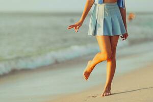 adolescente ragazze gambe su il spiaggia avvicinamento. ragazza a piedi su il spiaggia foto