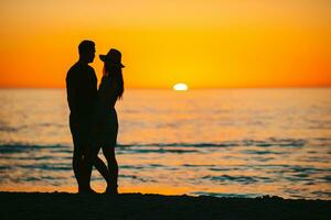 contento coppia su il spiaggia a bellissimo tramonto su sfondo foto