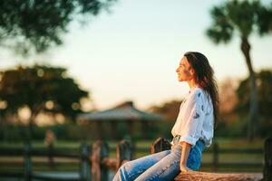 ritratto di contento giovane donna all'aperto nel il parco a tramonto foto