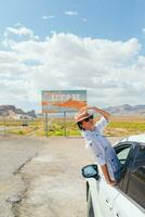 bellissimo donna su sua viaggio di il macchina. benvenuto per Utah strada cartello. grande benvenuto cartello saluta viaggi nel monumento valle, Utah foto