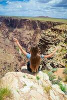 indietro Visualizza di ragazza su un' ripido scogliera assunzione nel il sorprendente Visualizza al di sopra di famoso mille dollari canyon su un' bellissimo soleggiato giorno, mille dollari canyon nazionale parco, Arizona, Stati Uniti d'America foto