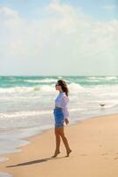 giovane contento donna a piedi su il spiaggia foto