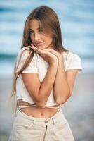 adorabile giovane ragazza con bellissimo lungo capelli godere tropicale spiaggia vacanza. il ragazza su il riva del mare a tramonto foto