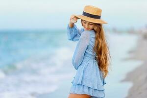 bellissimo adolescente ragazza su tropicale riva del mare a tramonto. bellissimo poco ragazza nel vestito a spiaggia avendo divertimento. contento ragazza godere estate vacanza sfondo il blu cielo e turchese acqua nel il mare foto