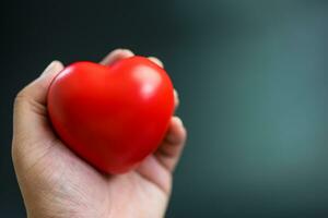 uomo Tenere un' rosso cuore su un' nero sfondo. relazione, Salute, e vita concetti. foto