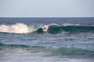 surfisti che cavalcano un'onda sulla spiaggia di arpoador a rio de janeiro, brasile foto